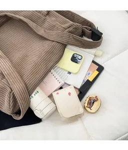 Detail shot of a large brown corduroy tote bag filled with daily essentials on white bedding