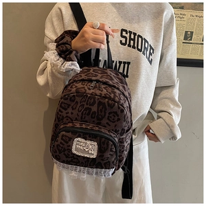 Detail of leopard print backpack with white lace trim and bow embroidery patch