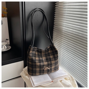 Macro detail of retro plaid bucket bag with gold bow ornament and leather handles