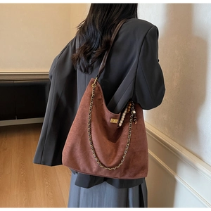 On-body view of large caramel suede tote bag with gold chain and beaded charm