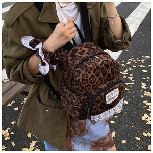 Close-up of leopard print mini backpack with white lace trim and front zipper pocket
