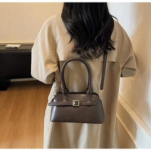 Detailed view of dark brown leather crossbody bag styled with a khaki trench coat