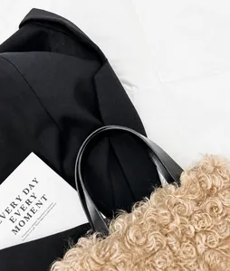 Close-up of beige plush faux fur bucket bag with black leather handle details