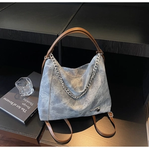 Detail view of washed grey canvas bag featuring brown leather straps and silver metal chain