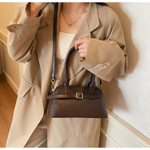Detail of deep brown leather shoulder bag with gold buckle and adjustable strap