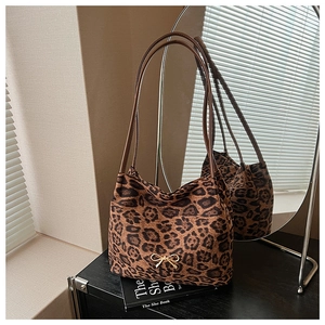 Detail of leopard print shoulder bag with small gold bow on minimalist shelf