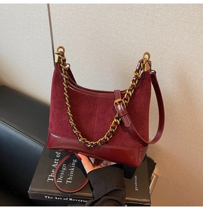 Detail of burgundy patchwork dumpling bag featuring suede finish and gold metal chain