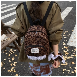 Detail of leopard print backpack featuring white lace trim and adjustable black straps