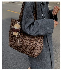 Leopard print canvas tote bag shown worn over the shoulder with a plush bear charm
