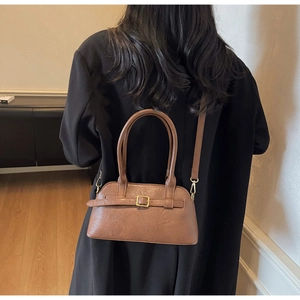 Brown leather boston bag detail with decorative belt strap and gold buckle on a model