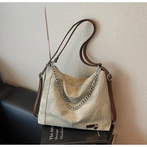 Detailed macro view of retro light green suede tote bag with silver chain and heart charm