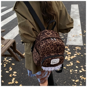 Detail view of leopard print backpack with white lace trim in an autumn street scene