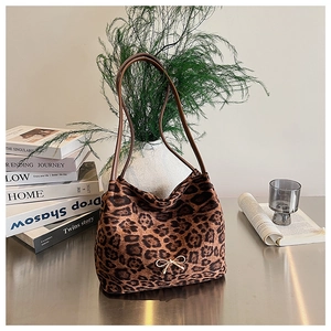 Detail of leopard print tote bag with gold bow accent on a stylish desk setup