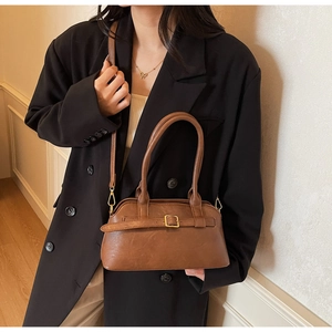 Detailed view of brown PU leather shoulder bag with gold buckle on a black blazer