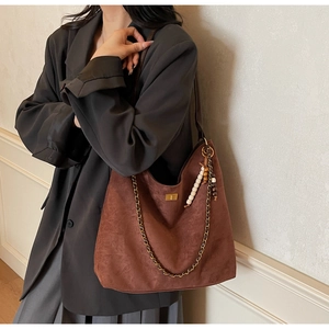 Detail of coffee brown hobo bag with suede texture and golden chain with wooden beads