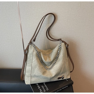Detail of beige hobo bag with thick silver chain, heart pendant and brown leather straps
