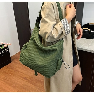 Close-up of a large green corduroy tote bag with adjustable strap shown from a side view
