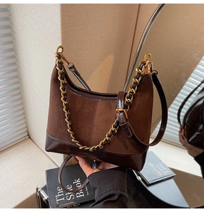 Detail of dark brown hobo bag showing suede texture, leather trim, and gold chain strap