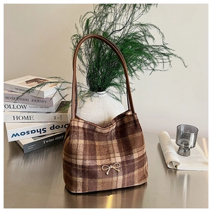 Detailed view of a retro brown checkered tote bag with a golden bow and leather straps