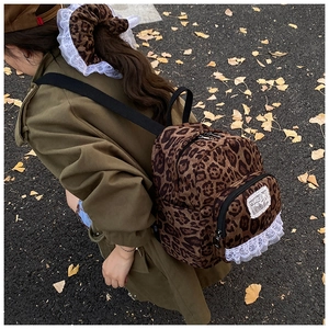 Detail showing retro leopard print backpack with white lace trim in an autumn outdoor setting
