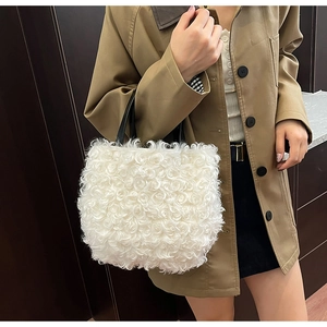 Close-up of white rose-textured plush tote bag featuring elegant black leather handles