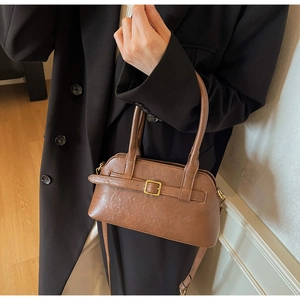 Close-up of brown PU leather handbag with gold buckle detail and detachable shoulder strap