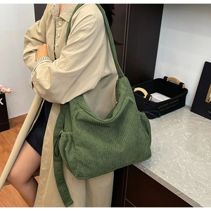 Detail of dark green corduroy tote bag showing retro texture and side drawstring knot