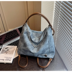 Detail of vintage blue tote bag with brown leather straps and silver chain decoration