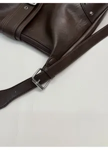 Detail of adjustable silver buckle on dark brown leather strap with neat stitching
