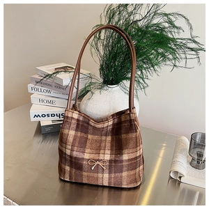 Close-up of brown plaid bucket bag with wool texture and a delicate golden bow clasp
