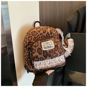 Detail of leopard print mini backpack featuring white lace trim and embroidered patch