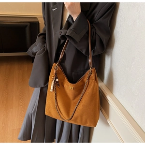 Detailed view of brown suede tote bag with gold chain and wooden bead charm detail