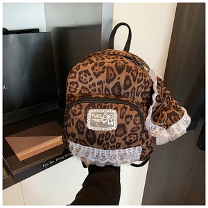 Close-up of leopard print backpack with white lace trim and embroidery detail