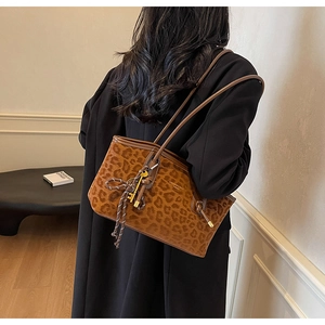 Détail du sac cabas léopard avec bandoulière en similicuir marron et breloques dorées