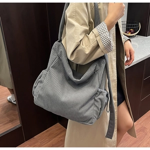 Detail view of grey corduroy tote bag showing soft ribbed texture and side drawstring pocket