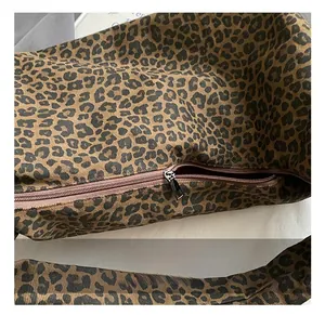Macro detail of the metal zipper and leopard print fabric texture on the shoulder bag