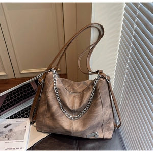 Macro detail of vintage brown tote bag texture with silver chain and heart charm