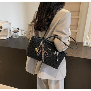 Détail d'un sac cabas léopard vintage avec breloque dorée et bandoulière tressée