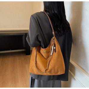 Detail of caramel suede Hobo bag with wide leather strap and decorative wood bead charm