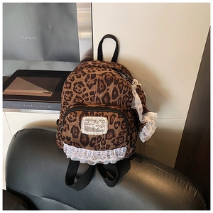 Close-up of retro leopard print backpack with white lace trim and vintage art book decor