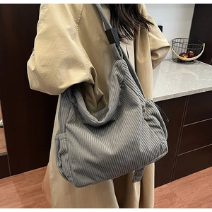 Detail view of large grey corduroy tote bag worn on shoulder for casual styling