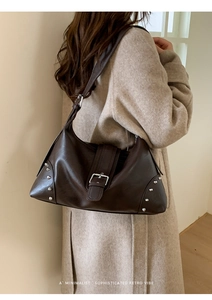 Detail of dark brown retro leather tote bag featuring silver rivets and a buckle strap