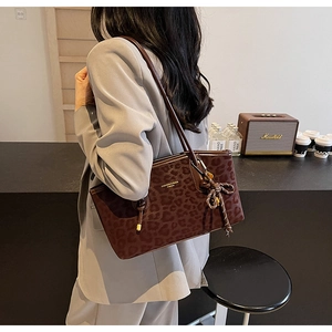 Détail du cabas vintage à motif léopard avec breloque tissée sur un sac à bandoulière