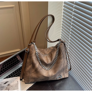 Close-up of vintage brown leather tote bag with silver chain and heart pendant detail