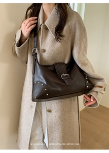 Detail of silver rivets and buckle closure on a dark brown leather shoulder bag