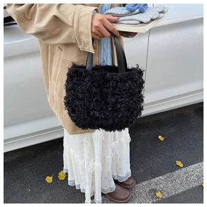Scatto street style all'aperto di una borsa tote nera in pelliccia sintetica