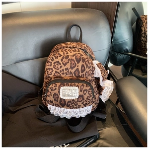Detail of leopard print backpack featuring white lace edges and decorative brand patch
