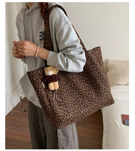 Detail of leopard print canvas tote bag featuring a cute teddy bear charm accessory