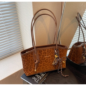 Détail du sac fourre-tout léopard avec texture daim et bordures en cuir sur livre