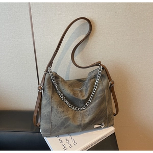 Detail of vintage hobo bag texture with silver chain and brown strap on a book